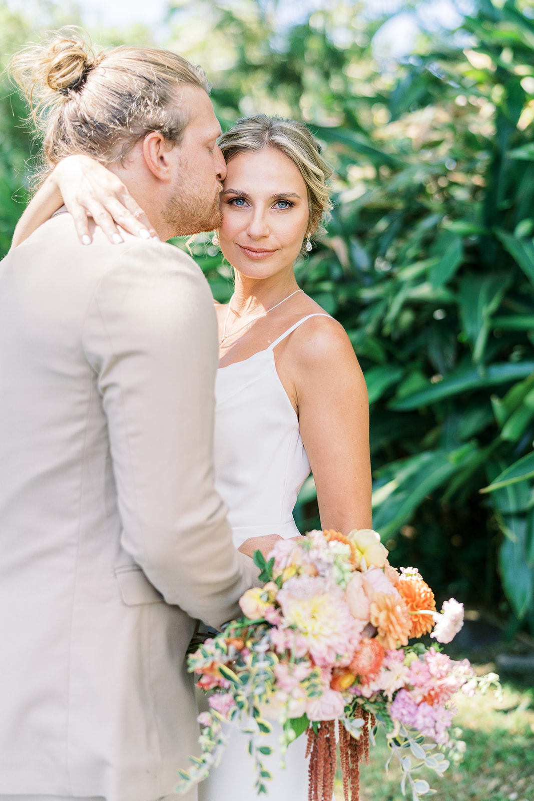 groom kissing bride with gorgeous lush hawaiian background